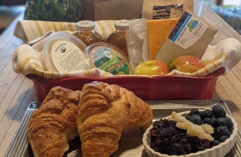 Locally sourced food basket with cheese, croissants, chocolate, fruit, and more.